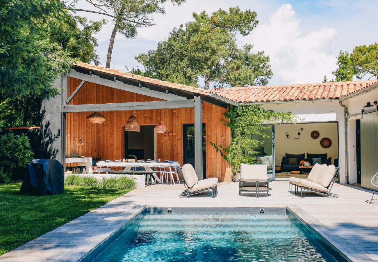 Terrasse en bois avec fauteuils et vue sur piscine et jardin boisé